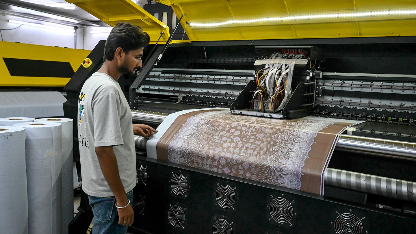 A worker checks the design on a sublimation textile printer at a garment factory in Amritsar, India on July 4, 2025.