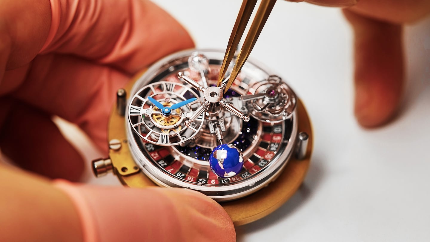 A watchmaker uses tweezers to carefully assemble the mechanical components of a luxury watch movement.